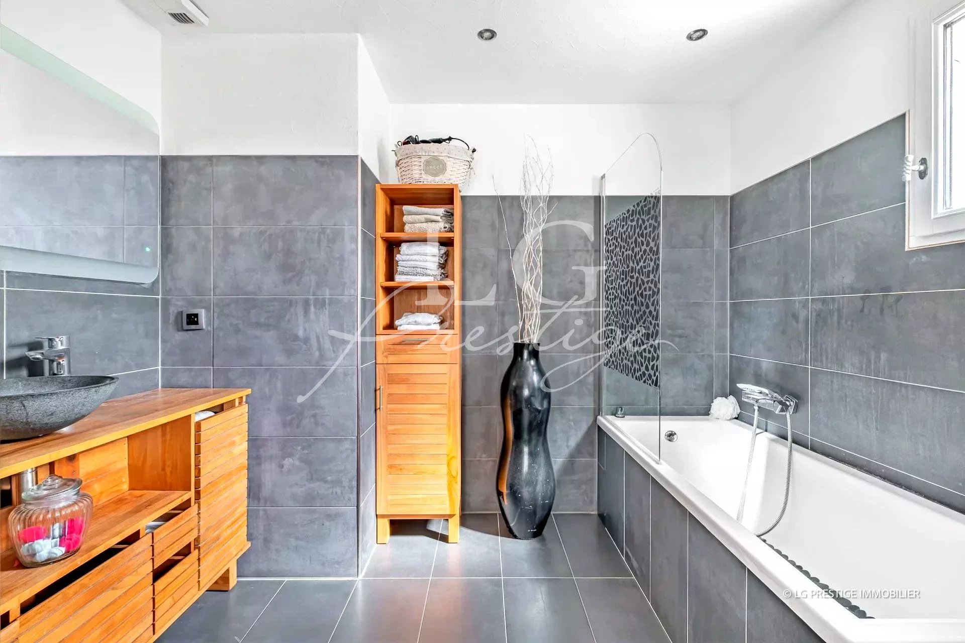 Salle de bain moderne Salle de bain moderne avec baignoire et douche, décorée de carrelage gris.