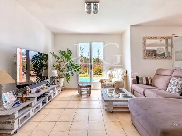 Intérieur d'une villa à Callian avec salon lumineux, canapé et vue sur la piscine extérieure.