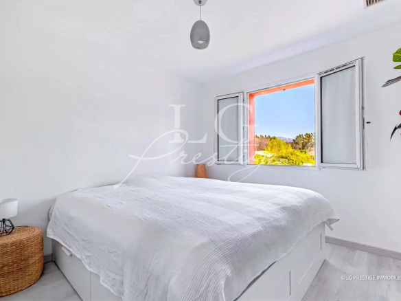 Chambre lumineuse avec lit double et fenêtre donnant sur la nature.