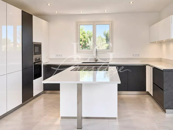 Modern and bright kitchen of a contemporary villa in Montauroux, with central island and windows.