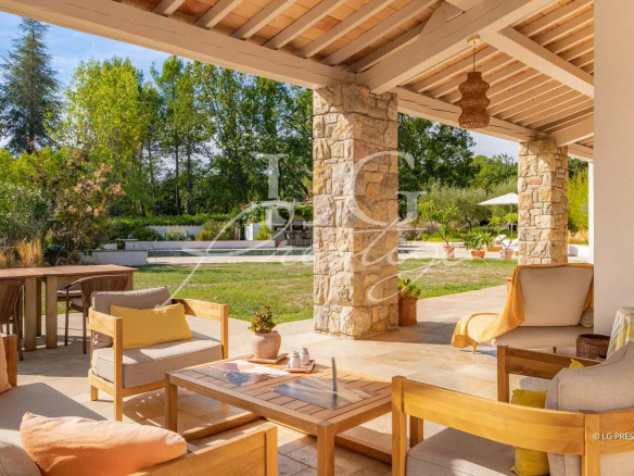 Terrasse d'une propriété provençale avec mobilier en bois et vue sur un jardin verdoyant à Fayence.