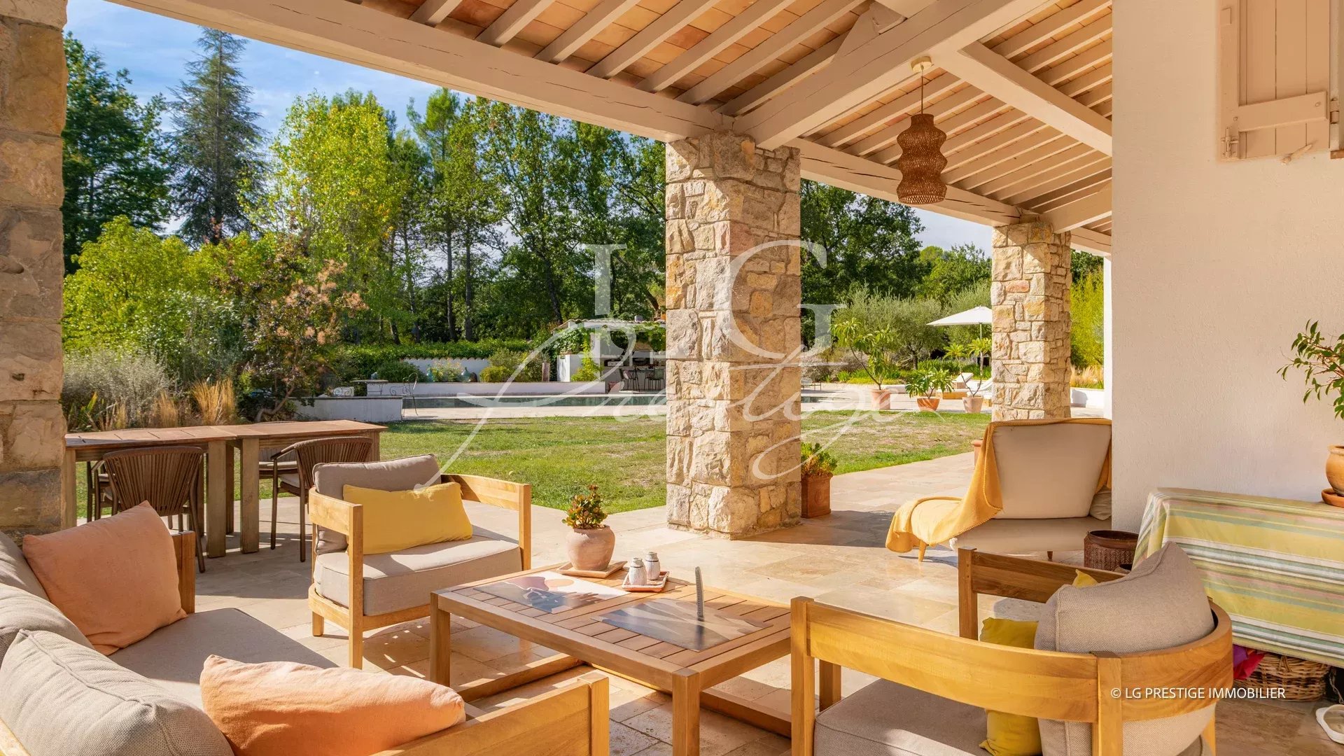 Terrasse d'une propriété provençale avec mobilier en bois et vue sur un jardin verdoyant à Fayence.