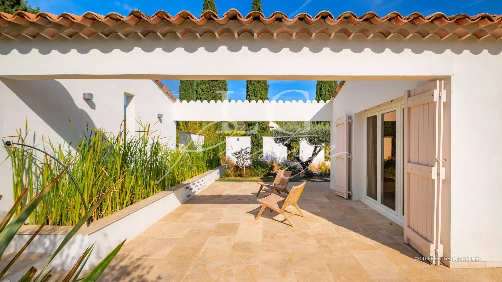 Terrasse d'une propriété provençale avec chaises en bois et végétation, Fayence