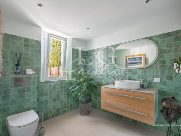 Salle de bain moderne avec carrelage vert et meuble en bois, lumière naturelle