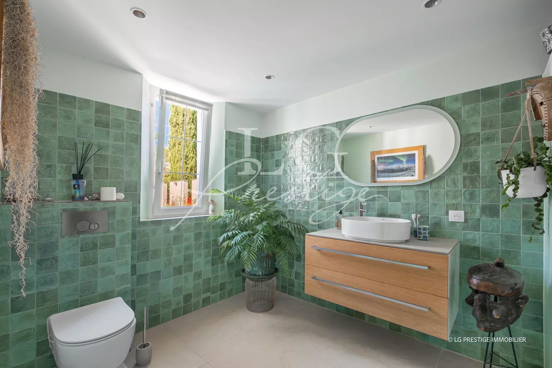 Salle de bain moderne avec carrelage vert et meuble en bois, lumière naturelle