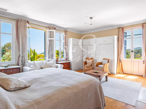Chambre lumineuse d'une villa avec vue sur la mer à Mandelieu-la-Napoule, fenêtres ouvertes et mobilier élégant.