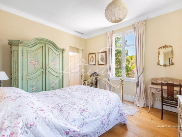 Chambre d'une villa à Mandelieu-la-Napoule avec lit et mobilier ancien.