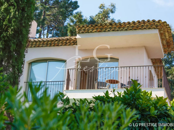 Modern villa with balcony in Théoule-sur-Mer, surrounded by greenery.