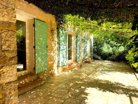 Entrée d'une bastide provençale avec volets verts et ombre de feuillage, Fayence.