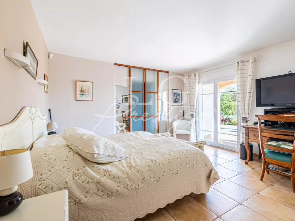 Chambre spacieuse d'une villa avec lit, télévision et accès à l'extérieur.