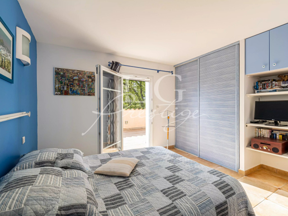 Chambre d'une villa avec accès à l'extérieur, murs bleus et meubles intégrés.