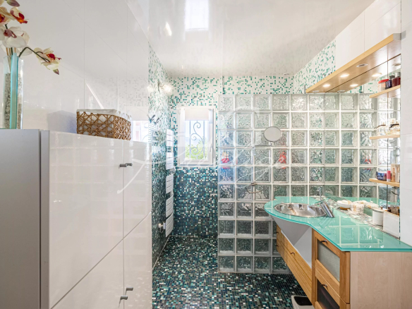 Salle de bain moderne avec murs en mosaïque et lavabo en verre.
