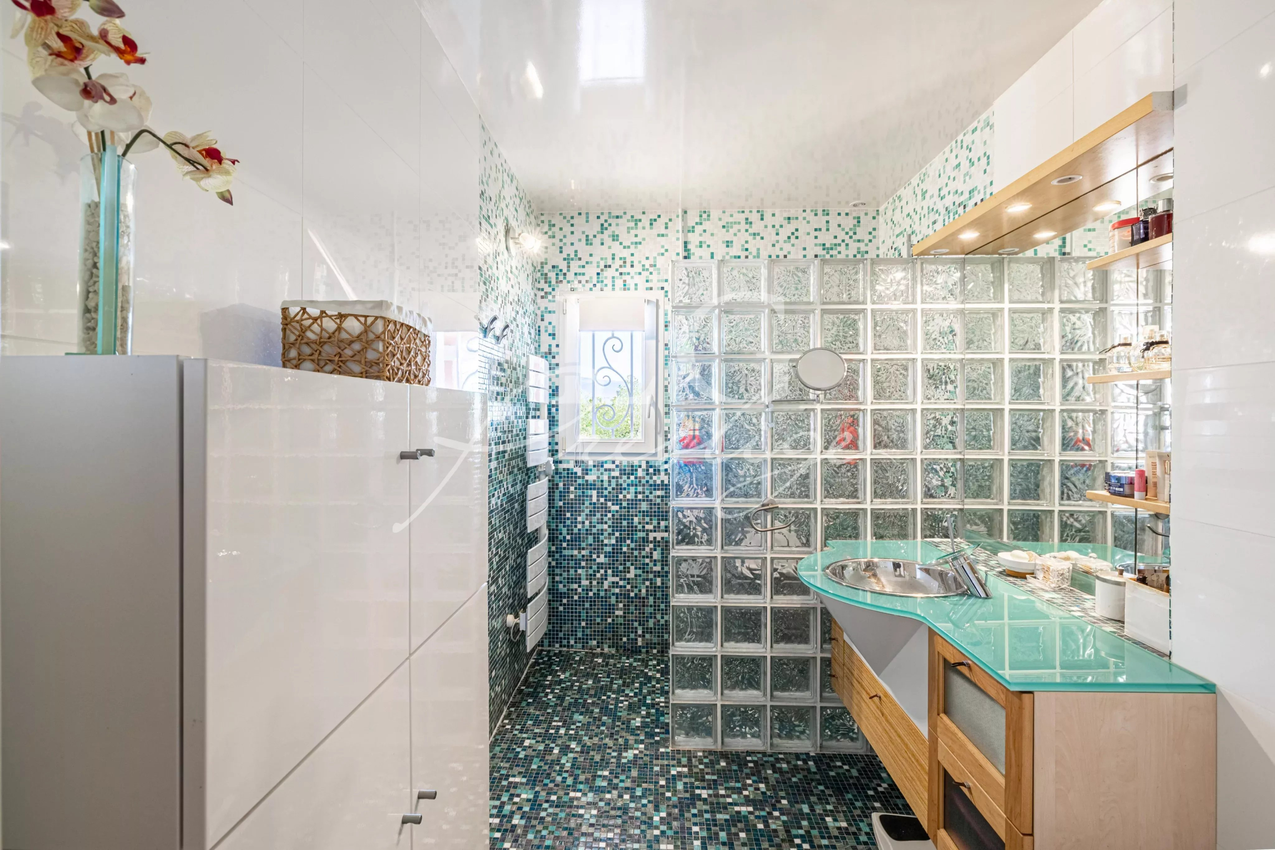 Salle de bain de la villa à Fayence Salle de bain moderne avec murs en mosaïque et lavabo en verre.