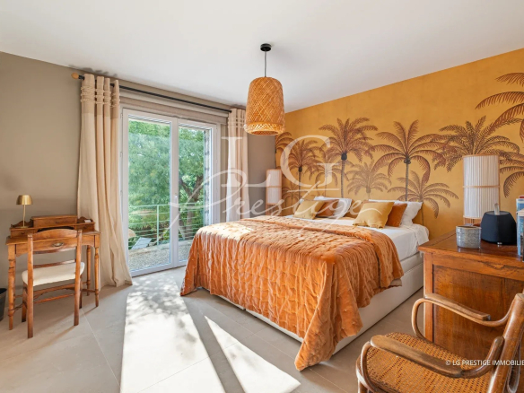 Room in a villa in Mandelieu-la-Napoule with warm decor and a view of nature.