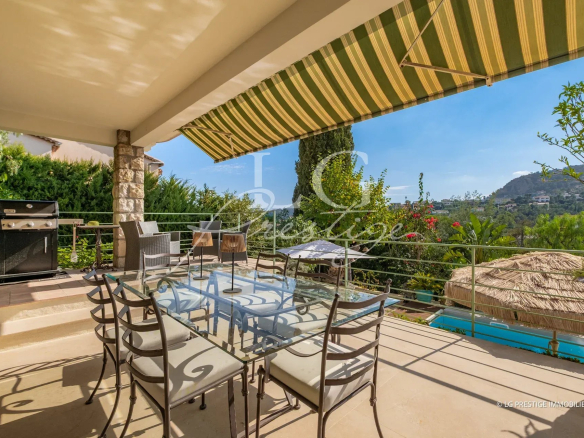 Villa terrace with view, table and chairs, barbecue, swimming pool nearby.