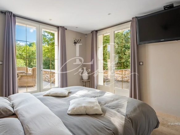 Chambre d'une villa à Callian avec fenêtres donnant sur un espace extérieur verdoyant.