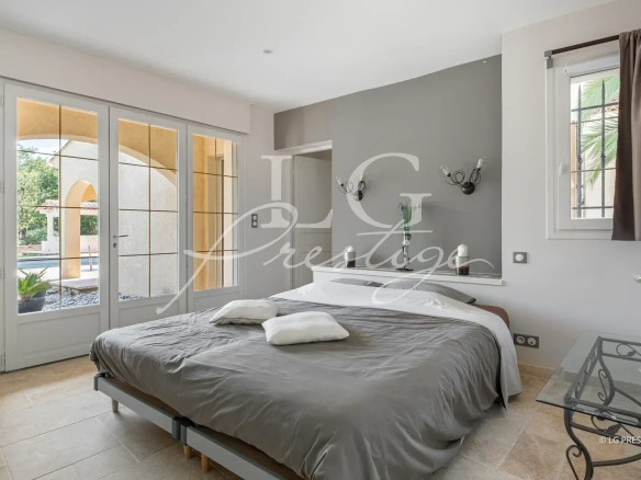 Chambre d'une villa élégante à Callian avec lit, fenêtres et décor moderne.