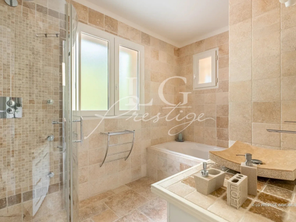 Salle de bain moderne avec douche et baignoire, carrelage beige.