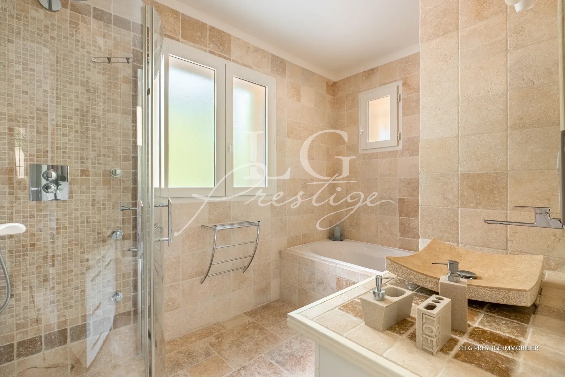 Salle de bain élégante dans une villa à Callian Salle de bain moderne avec douche et baignoire, carrelage beige.