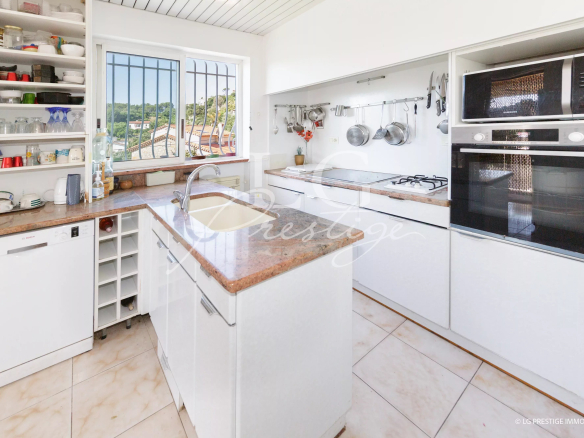 Cuisine moderne avec plans de travail en marbre et vue sur la nature.