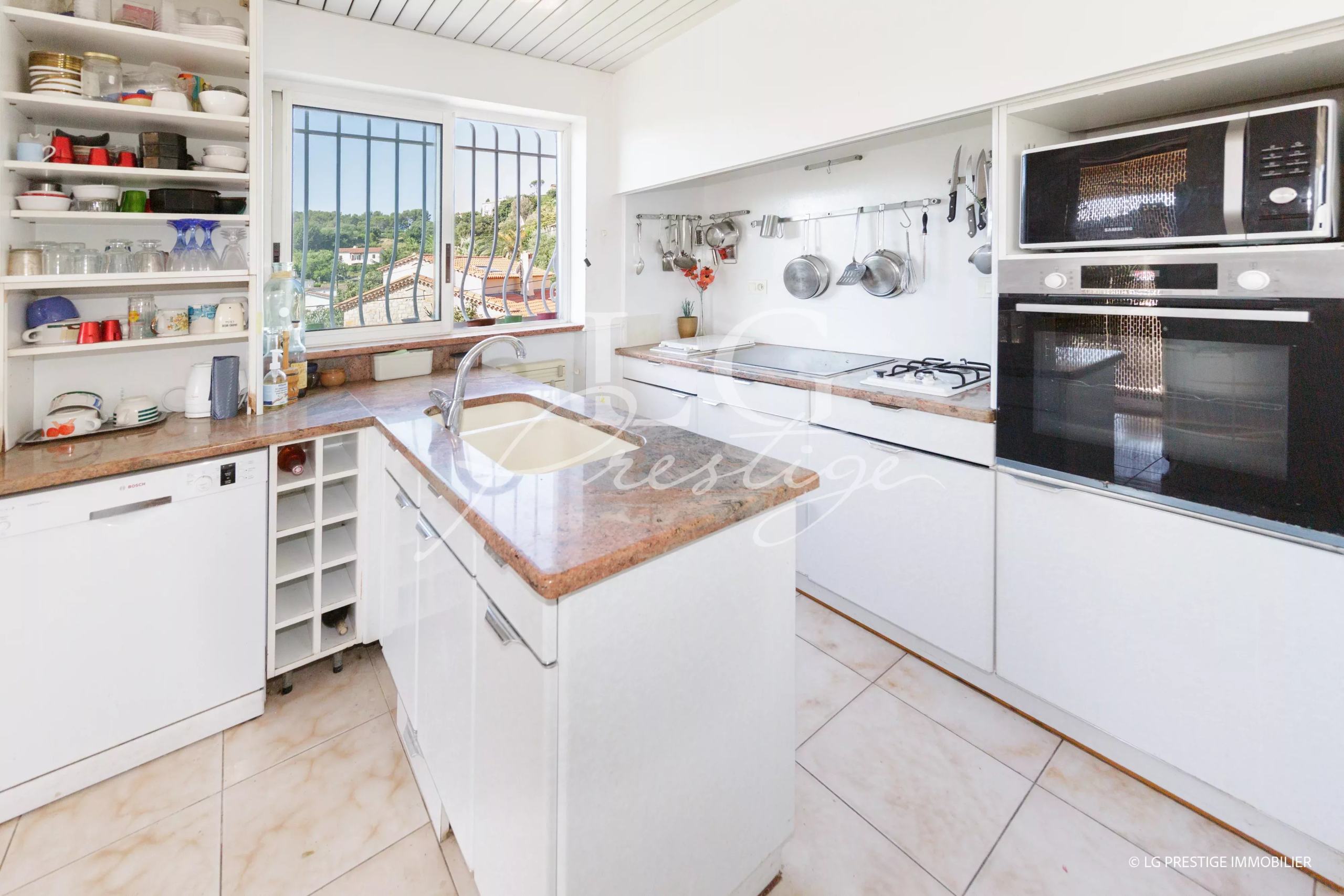 Cuisine moderne avec plans de travail en marbre et vue sur la nature.