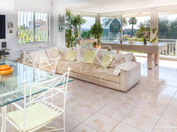 Intérieur d'une villa spacieuse avec salon lumineux et vue sur le jardin.