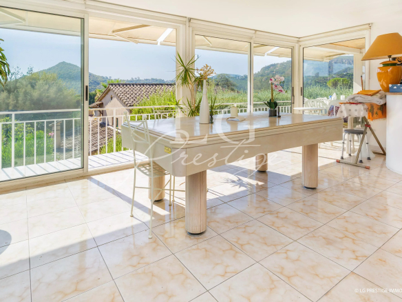 Intérieur lumineux d'une villa avec table à manger et vue sur la nature.