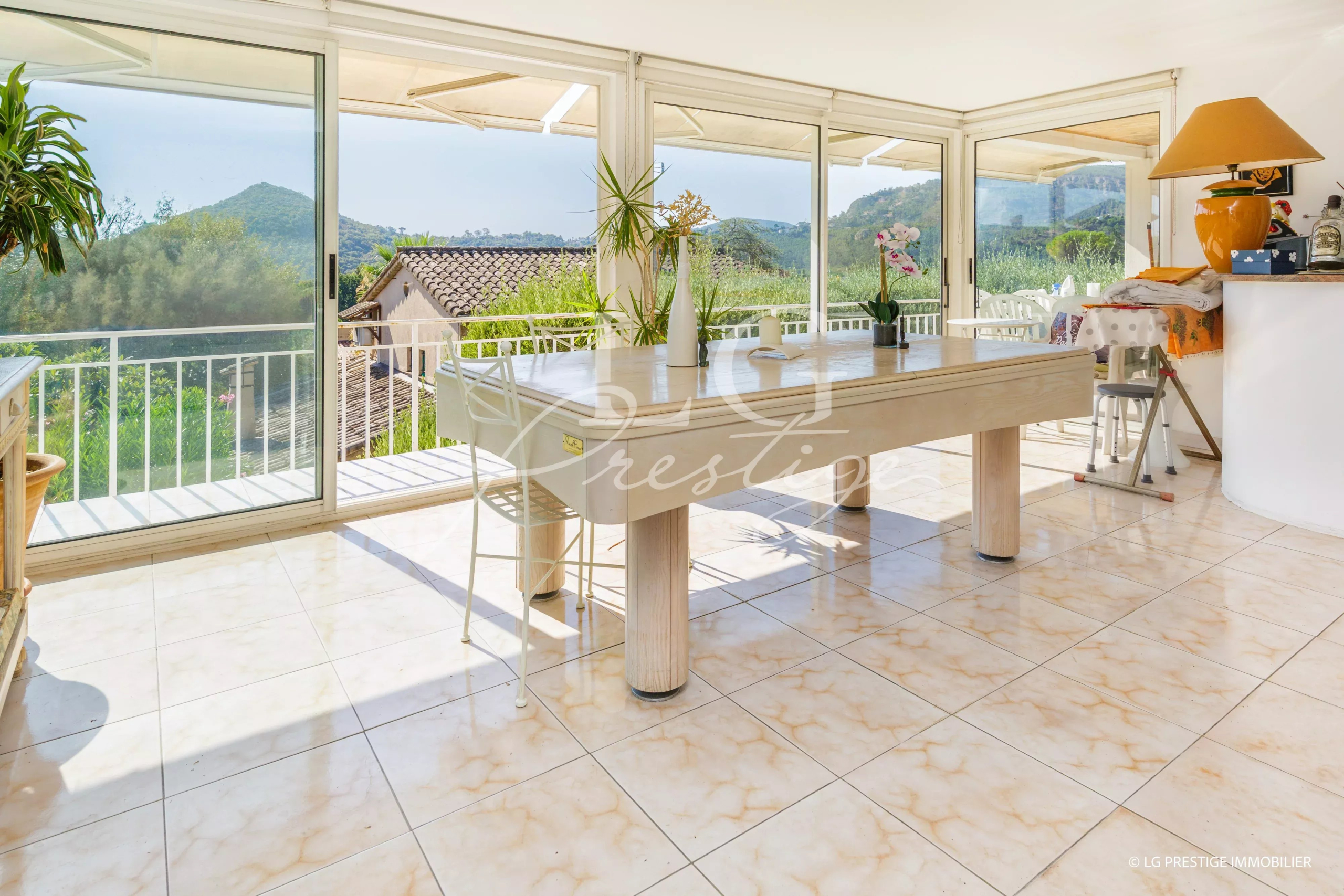 Intérieur lumineux d'une villa avec table à manger et vue sur la nature.