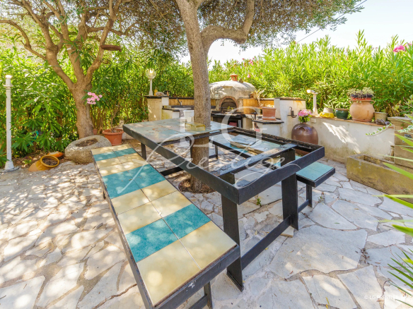 Espace extérieur d'une villa avec table en pierre et arbres, situé à Mandelieu-la-Napoule.