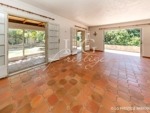 Interior of a villa to be renovated with terracotta tiles and large windows overlooking the garden.