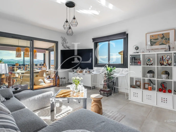 Intérieur d'une maison rénovée avec salon moderne et vue sur la mer et les montagnes.
