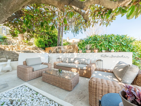 Espace extérieur avec mobilier en osier et décoration, entouré de verdure.