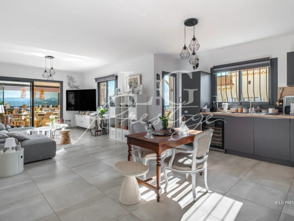 Intérieur d'une maison moderne avec cuisine ouverte et salon, vue sur la mer et les montagnes.