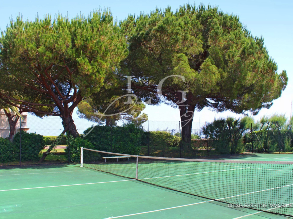 Terrain de tennis dans une résidence en bord de mer avec arbres et végétation