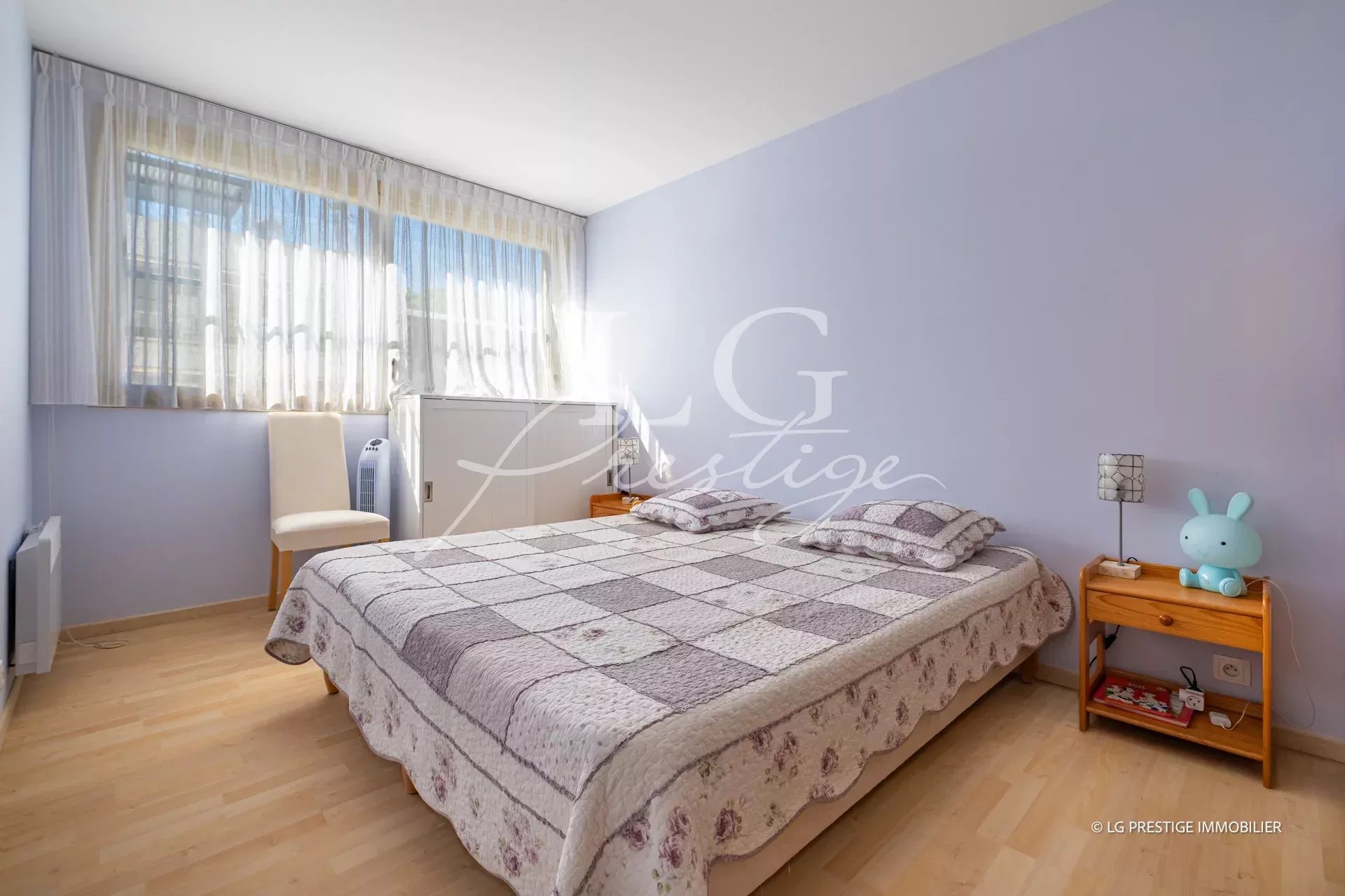 Chambre d’appartement à Mandelieu-La-Napoule Chambre d'un appartement avec lit double et fenêtres laissant entrer la lumière.