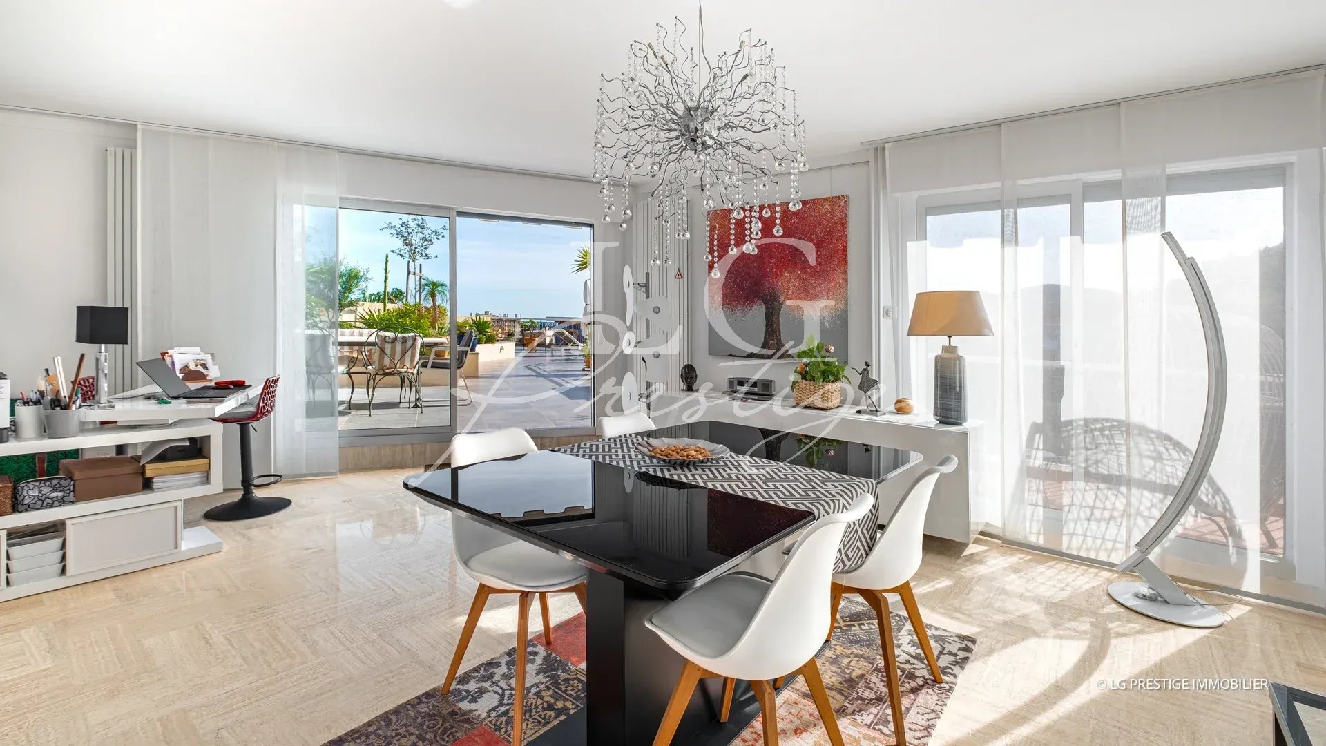 Intérieur d'un appartement lumineux avec salle à manger et accès à une terrasse. Vue sur la mer.