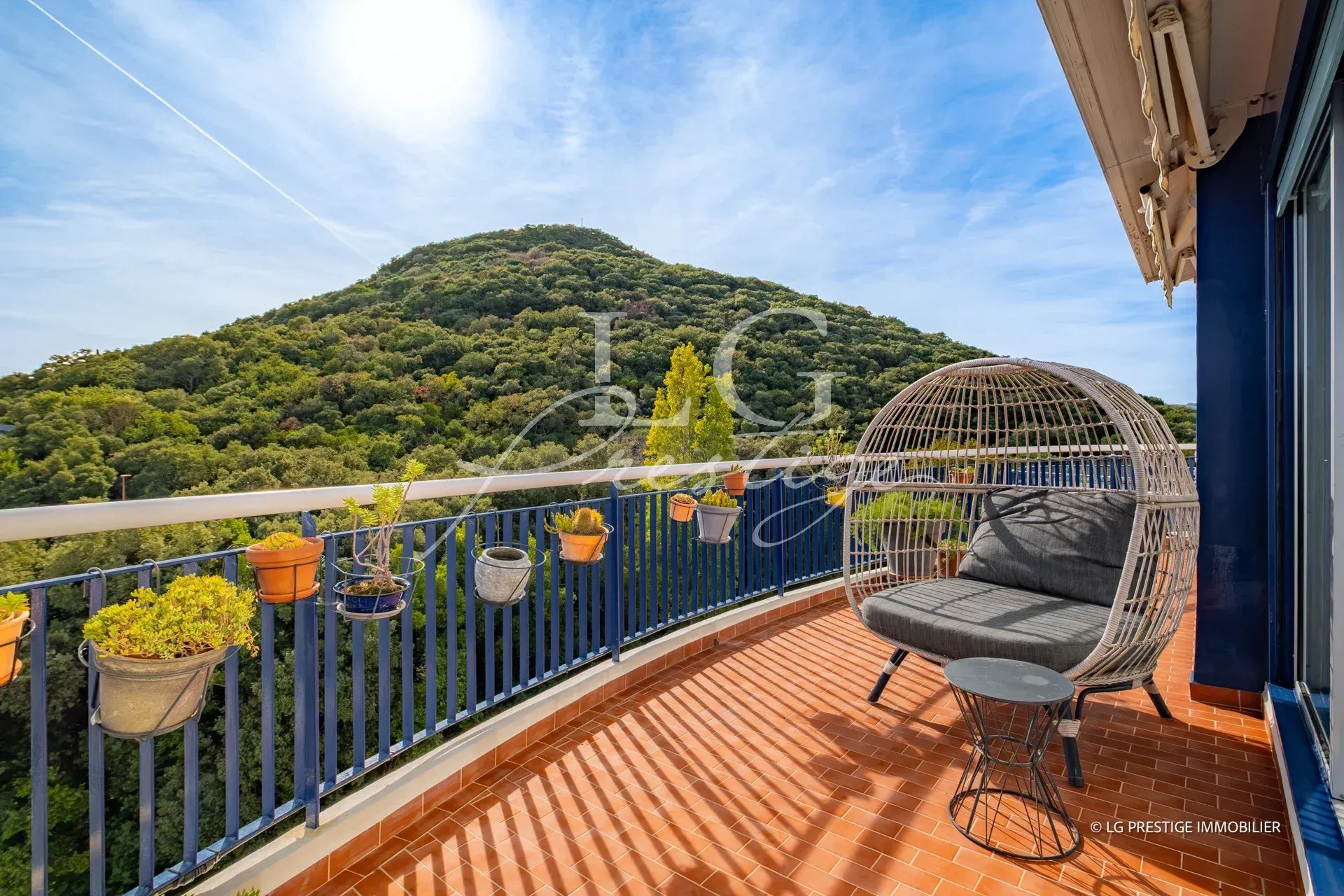 Terrasse d'un appartement avec vue sur une colline verdoyante à Mandelieu-la-Napoule.