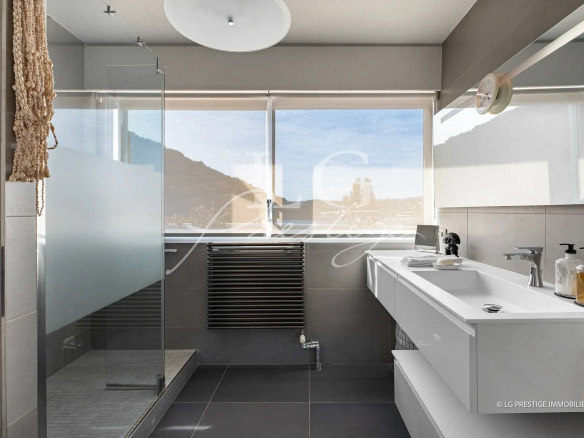 Salle de bain moderne avec douche et lavabo, vue sur la mer à Mandelieu-la-Napoule.