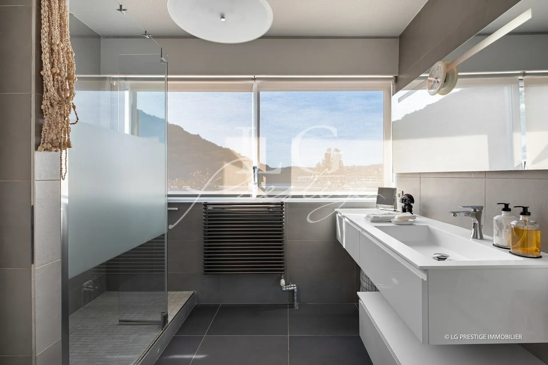 Salle de bain moderne avec douche et lavabo, vue sur la mer à Mandelieu-la-Napoule.