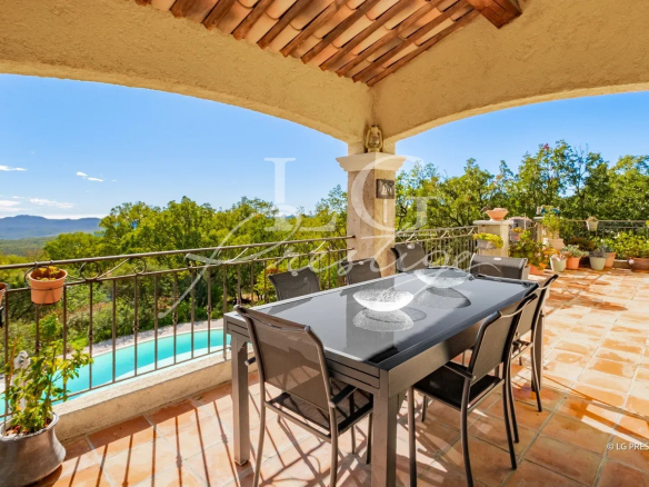Terrasse couverte avec table et chaises, vue sur jardin et piscine, environnement naturel à Fayence.