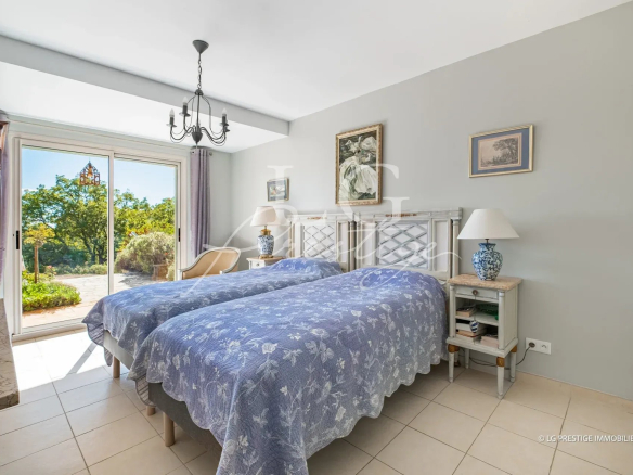 Chambre d'une villa avec deux lits simples, décorée sobrement, ouverte sur un jardin verdoyant.