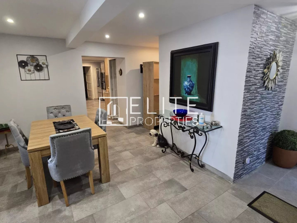 Dining area with a wooden table and four gray upholstered chairs, accented by wall art and a stone feature wall in a modern home.