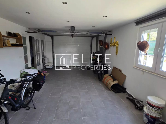 Bright home garage with bicycles on the left, storage shelves along the wall, a white sectional door at the back, and a window with gold '4th' balloons on the right.