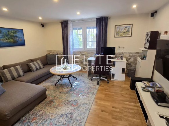 Cozy living room with an L-shaped brown sofa, striped cushions, a round coffee table, and a colorful patterned rug across hardwood floors.