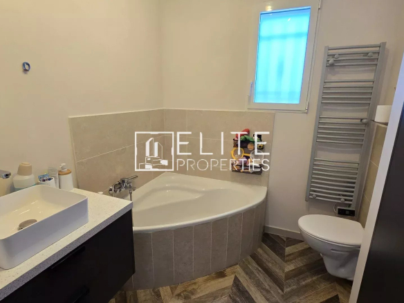 Modern bathroom with a corner tub, white vessel sink on a speckled countertop, and a wall-mounted mirror.