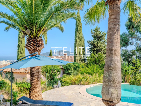 Maison de charme avec piscine et vue mer à Mandelieu-la-Napoule, entourée de palmiers et verdure.