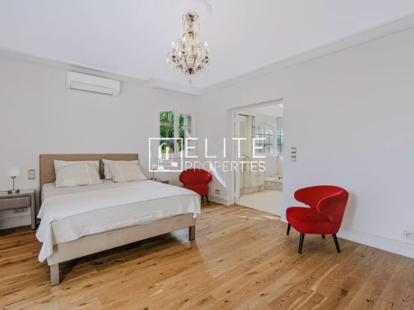Chambre d'une maison de charme à Mandelieu-la-Napoule, avec lit double et fauteuils rouges.