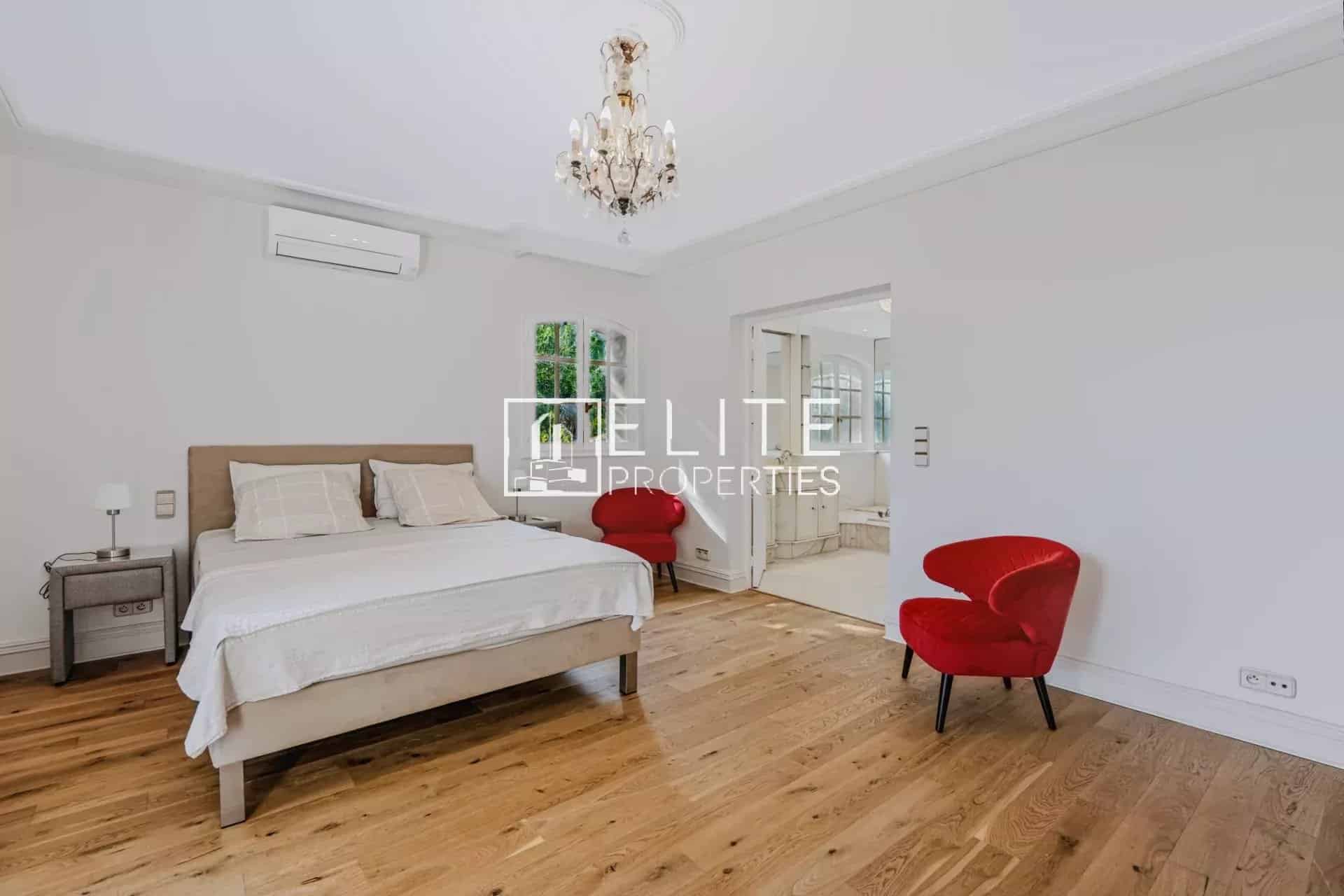 Chambre élégante à Mandelieu-la-Napoule Chambre d'une maison de charme à Mandelieu-la-Napoule, avec lit double et fauteuils rouges.