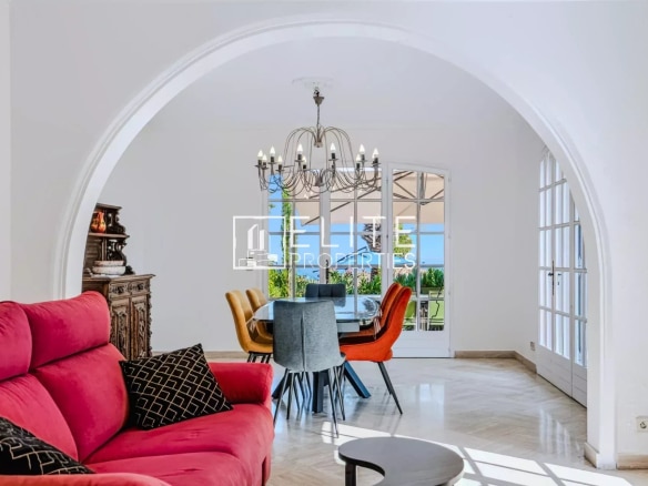 Intérieur d'une maison avec un salon rouge et une salle à manger lumineuse, vue sur la mer à Mandelieu-la-Napoule.
