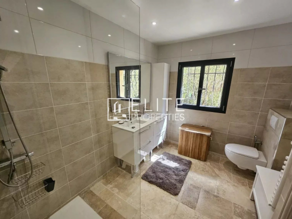 Modern bathroom with shower, vanity unit and bright window.